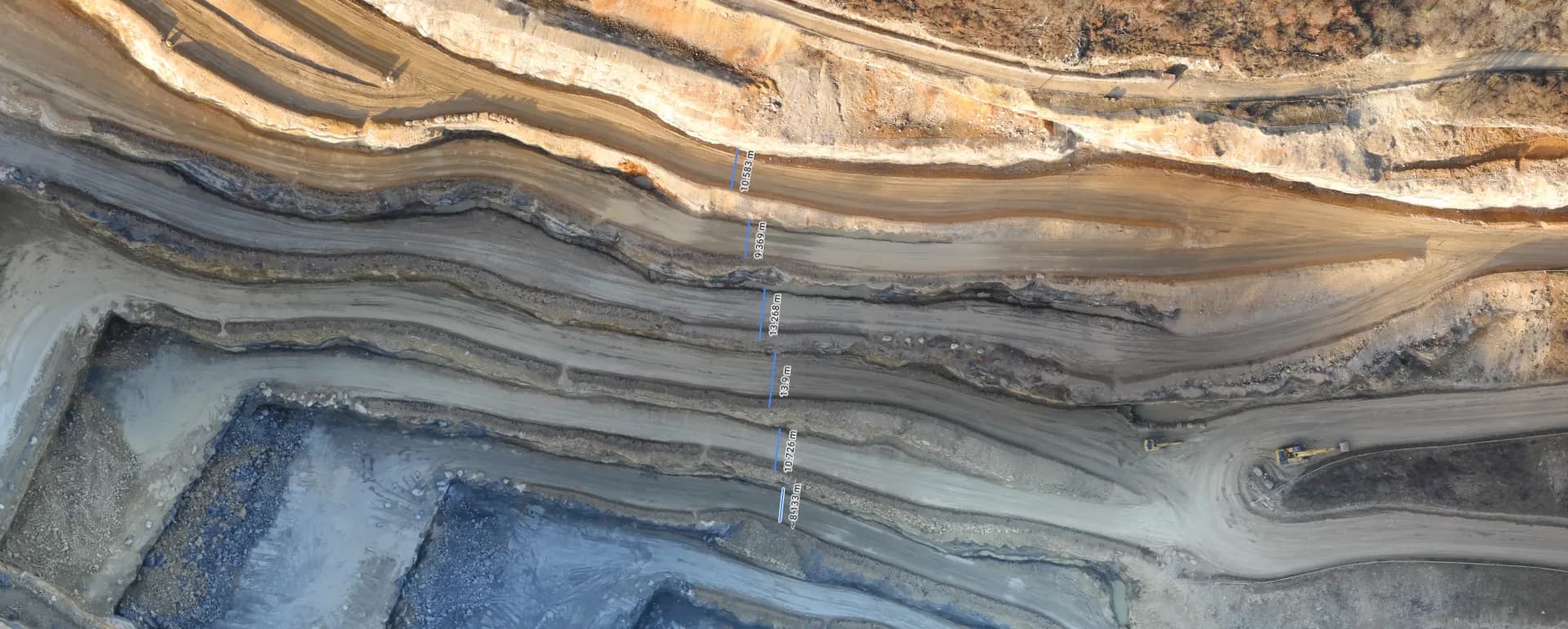 An orthomosaic of an open pit with bench widths measured and labelled along a section line.